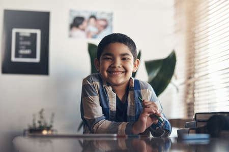 Im learning from home and I love it. Portrait of an adorable little boy completing a school assignment at home.の写真素材