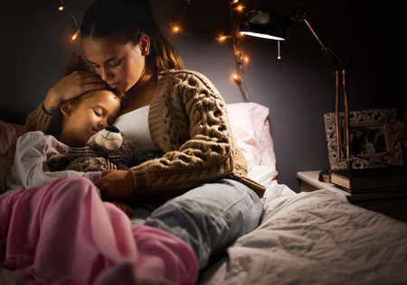 Dream sweet dreams my angel. Shot of a mother holding her daughter while she sleeps.の写真素材