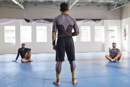Addressing his students. Rearview shot of an unrecognizable jiu jitsu sensei addressing his students...