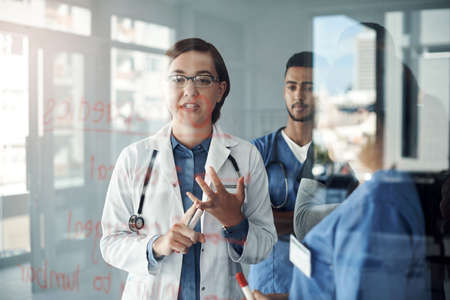 Class is in session. Shot a group of doctors discussing formulas in the office at work.の写真素材