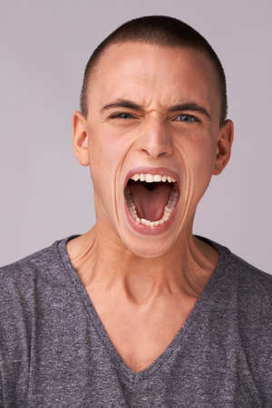 Silence is golden but shouting is fun. Studio shot of a handsome young man looking at the camera.の写真素材