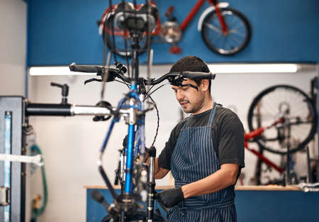 Giving your bike the attention it deserves. Shot of a man working in a bicycle repair shop.の写真素材