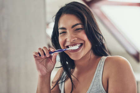 Fresh breath to start off a new day. Portrait of an attractive young woman brushing her teeth at home.の写真素材