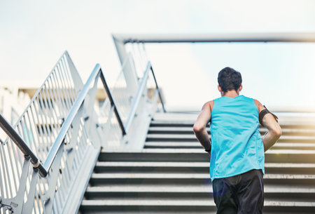 Upping his work rate. Rearview shot of a handsome young man working out in the city.の写真素材