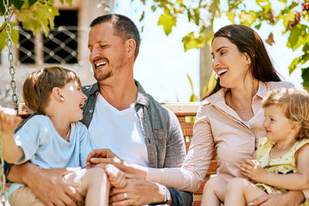 Give them a childhood to smile about. Shot of a family of four relaxing together on a garden swing.
