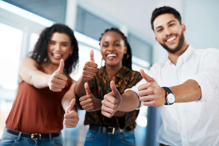 Thumbs up to opportunities. Cropped portrait of a diverse group of business colleagues standing together in the office and showing a thumbs up.の写真素材