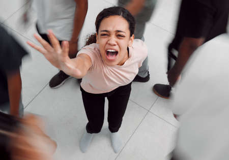 Hear me scream in agony. Shot of a young woman experiencing mental illness while being surrounded by people inside.の写真素材