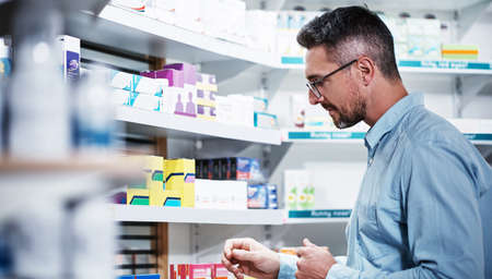 Browsing around for the right treatment. Shot of a mature man looking at products in a pharmacy.の写真素材