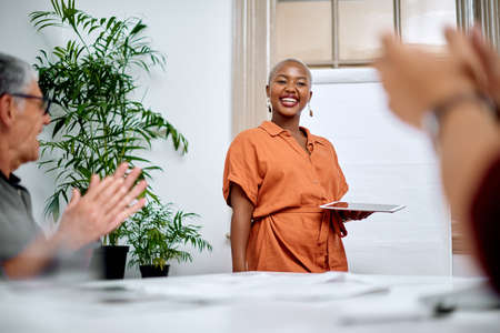 Shes delivered a memorable talk. Shot of a young businesswoman receiving applause from her colleagues during a meeting in an office.の写真素材