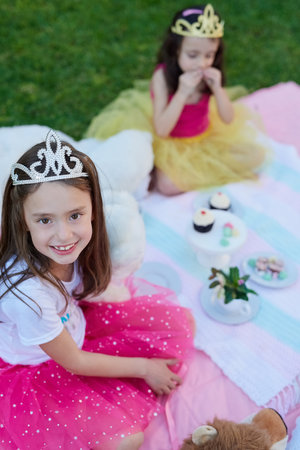 Even princesses enjoy picnics. Portrait of a little girl having a picnic with her sister outside.