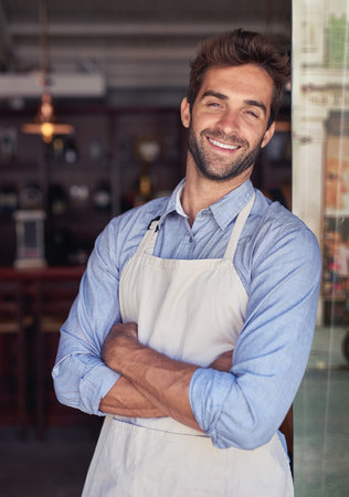 Ill make my coffee shop a success. Cropped portrait of a young barista standing in a coffee shop.の写真素材