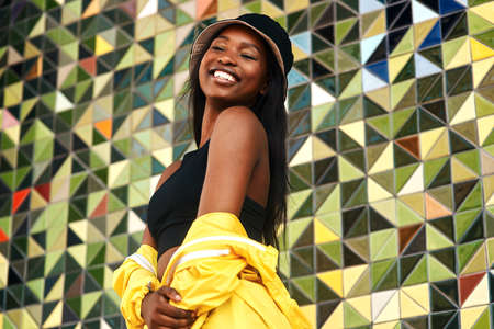 A smile a day keeps the blues away. Cropped shot of an attractive young woman standing alone against a brightly tiled wall during the day.の写真素材