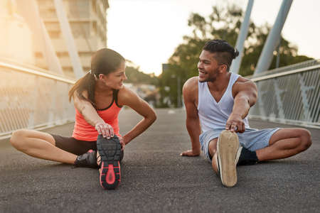 How you feeling. Shot of a young couple warming up on a bridge before their workout.の写真素材