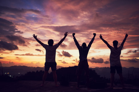 Embrace freedom with open arms. Rear view shot of a group of people standing outside with their arms outstretched.の写真素材
