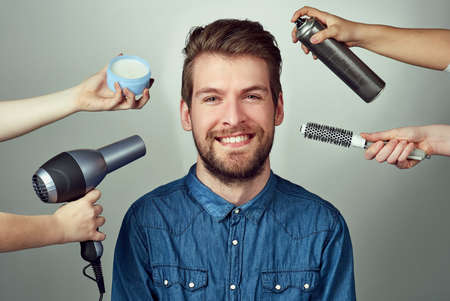 Mix up your look with a makeover. Studio portrait of a young man getting a hair makeover against a gray background.の写真素材