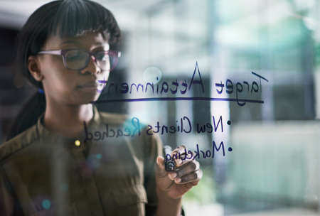 Business target plans. Shot of a young woman writing business notes on a window.の写真素材