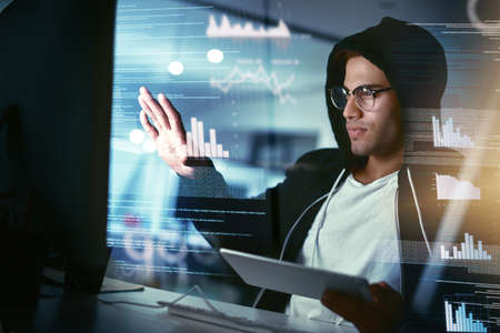 Hackers are the masters of stealth. Shot of a young hacker cracking a computer code in the dark.