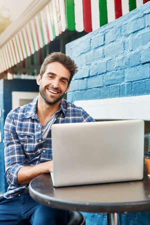 Chilling at the sidewalk cafe. Shot of a handsome young man sitting at a sidewalk cafe.の写真素材