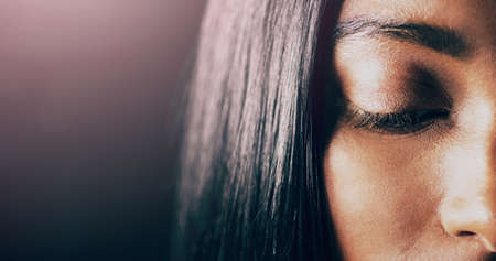 You dont have to look to see whats going on. Closeup shot of a beautiful young woman posing with her eyes closed against a dark background.の写真素材