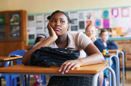Argh, its going to be a long day. Shot of a young girl sitting in her classroom at school and feeling bored.の写真素材