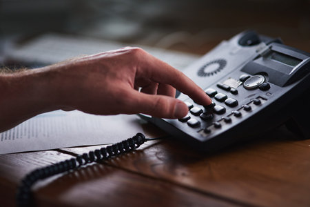 Success is a phonecall away. Shot of an unidentifiable businessman using a desk phone in the office.の写真素材