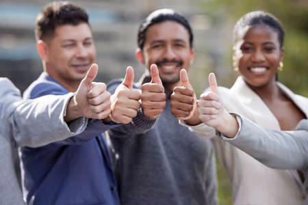 Its a yes from us. Portrait of a group of businesspeople showing a thumbs up outside.の写真素材