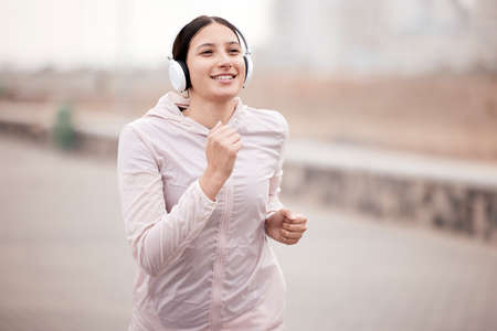 Good music, greater run. Shot of a young woman using headphones during her run on the promenade.