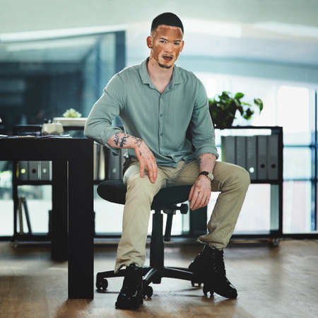 Im on the path to success. Shot of a young businessman sitting at a desk in an office at work.の写真素材