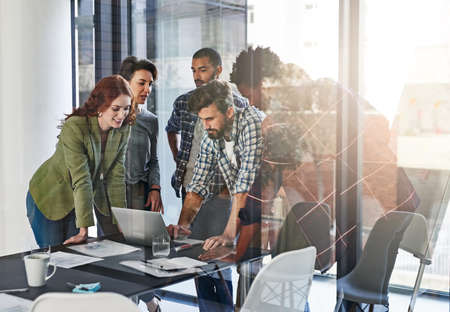 Bringing fresh ideas to the table. Shot of a group of colleagues working together on a laptop in an...