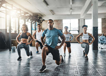Every step taken towards fitness pays off. Shot of a group of young people doing lunges together...