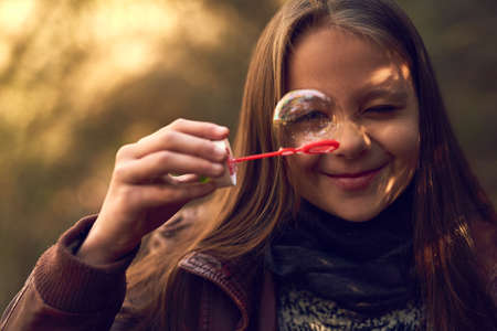 Bubble fun. Portrait of a young girl playing with bubbles outside.の写真素材
