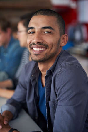 Hes an asset to the comapny. Portrait of an handsome young man sitting in an office with colleagues...
