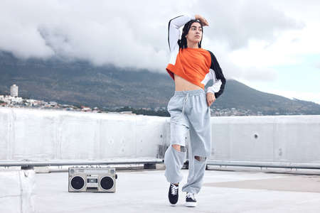 Dancing is my escape. Shot of a young woman out on a rooftop with a boombox.の写真素材