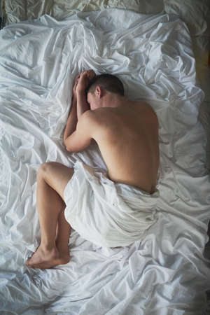 Sound asleep. Shot of a shirtless young man sleeping in his bedroom.