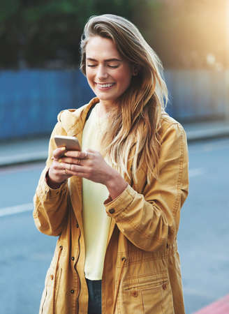 Ill have my friends out here in no time. Shot of a young woman using her cellphone while out in the...