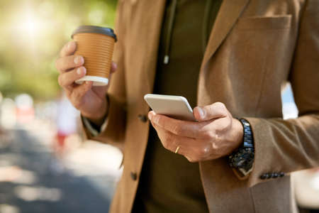 Staying in touch when hes away from the office. Cropped shot of an unrecognizable man sending a text message during his morning commute.の写真素材
