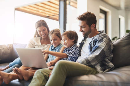 Connected online and as a family. Shot of a mother and father using a laptop with their son and...