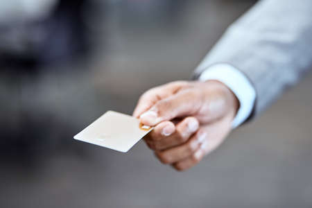 No need to ever carry cash again. Closeup shot of an unrecognizable businessman holding a credit card in an office.の写真素材