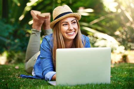 Thinking about her next article. Shot of an attractive young woman using her laptop while outside on...