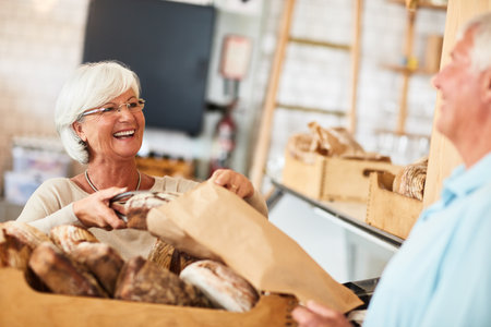 Hope you enjoy it because I enjoyed baking it. Shot of a happy senior woman serving a customer in a bakery.の写真素材