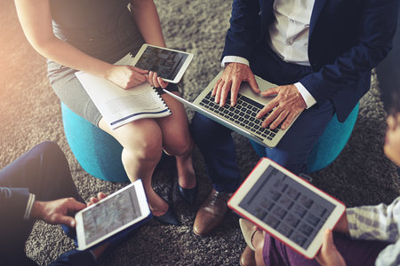 Technology brought the world closer as a whole. High angle shot of a group of businesspeople using their digital tablets.の写真素材