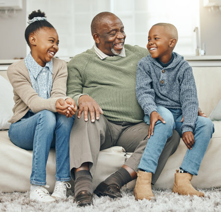 Thats how we did things back in the day. Shot of a grandfather bonding with his grandkids on a sofa at home.の写真素材