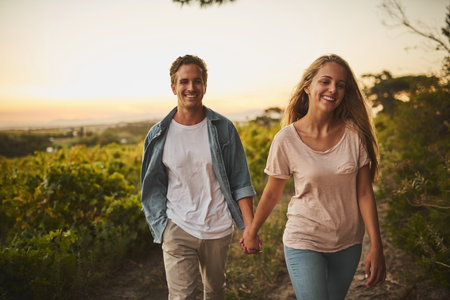 It feels like we started yesterday. Shot of a young couple walking through their crops and holding hands while smiling all the way.の写真素材