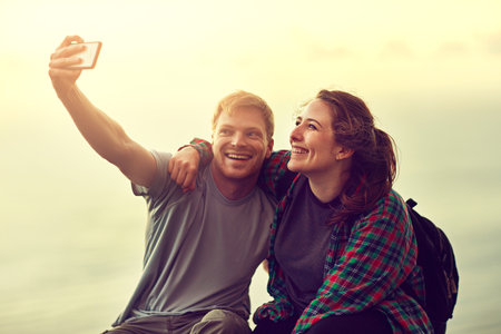 This is the day he proposed. Cropped shot of a young couple taking a selfie on a mountain top.の写真素材