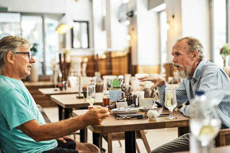 This place serves a great breakfast. Shot of two senior friends chatting at a table at their favorite cafe.の写真素材