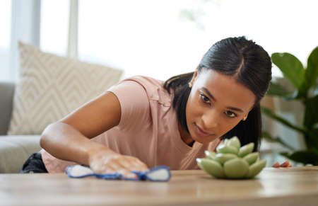 I almost missed a spot. Shot of a young woman cleaning a table at home.