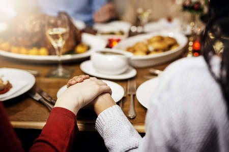 Nothing brings family together like Christmas lunch. Cropped shot of unrecognizable people holding hands in prayer before having a Christmas lunch together.の写真素材