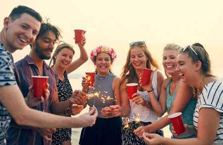 Making this summer day sparkle even more. Shot of young people hanging out at the beach.