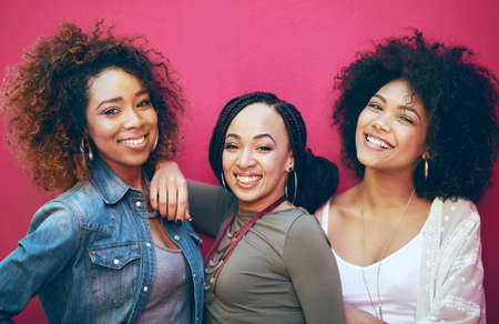 Best friends More like sisters. Portrait of a group of female friends posing against a pink background.の写真素材