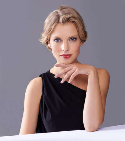 Ive been waiting for you..... A gorgeous young woman in an evening gown while isolated on a grey background.の写真素材